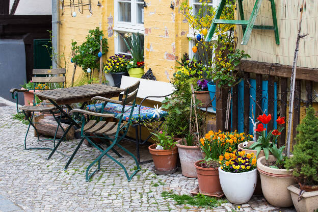 Tische, Stühle und Blumen vor einer Hauswand